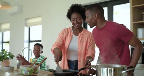 African American family cooking together in modern bright kitchen, parents preparing meal