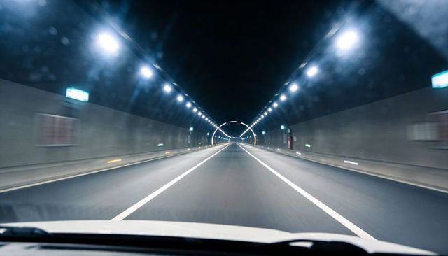 Driving through illuminated highway tunnel at night with vanishing point perspective
