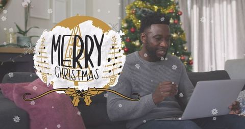 Man Using Laptop in Cozy Festive Home with Merry Christmas Overlay