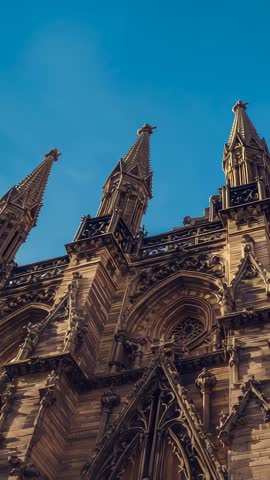 Vertical video tilting upward Gothic cathedral spires with intricate stone tracery