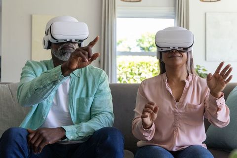 Mature African American Couple Using VR Headsets Reaching into Immersive Virtual World