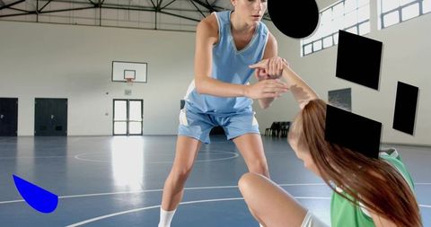 Women basketball players helping and defending on indoor court during competitive game
