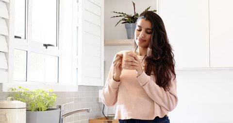Relaxed Woman Enjoying Coffee in Bright Home Kitchen