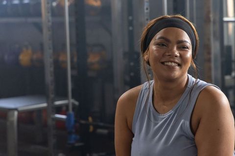 African american woman smiling and resting after strength workout in gym with kettlebells