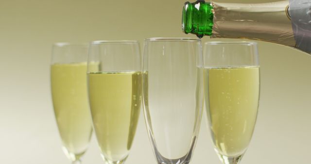 Image of champagne pouring into glass on yellow background. alcohol, beverage, drinks, party and celebration concept.