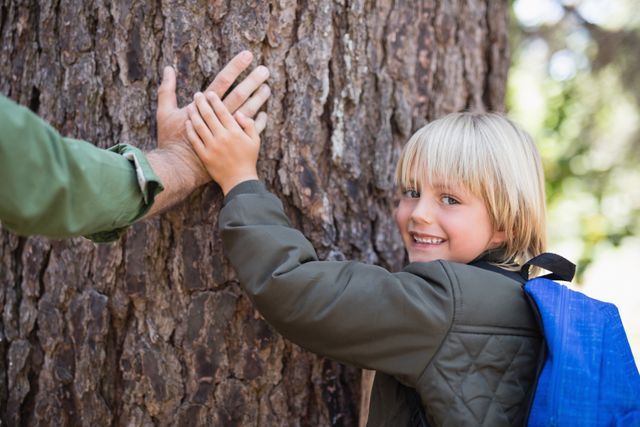 Boy and father enjoying time in forest, touching tree trunk. Perfect for themes of family bonding, outdoor activities, nature conservation, and childhood adventures. Ideal for use in environmental campaigns, family-oriented advertisements, and educational materials about nature.