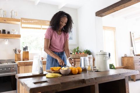 African american woman slicing fresh fruit on wooden island in rustic farmhouse kitchen