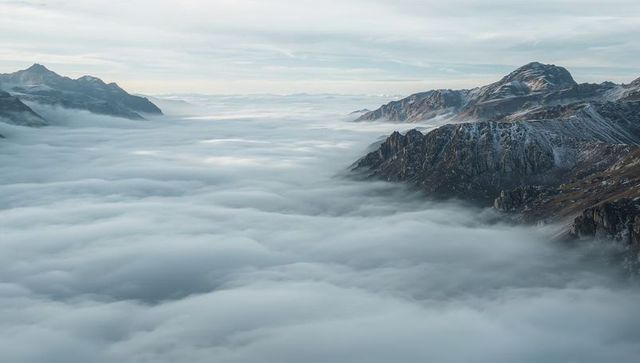 Rolling Clouds Flooding Alpine Valley with Snow-Dusted Ridgelines at Dawn