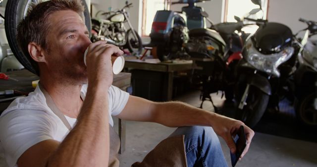 Mechanic Taking Coffee Break in Motorcycle Repair Shop - Download Free Stock Images Pikwizard.com