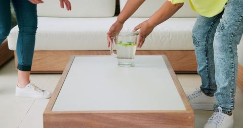People placing glass jug on coffee table in modern living room