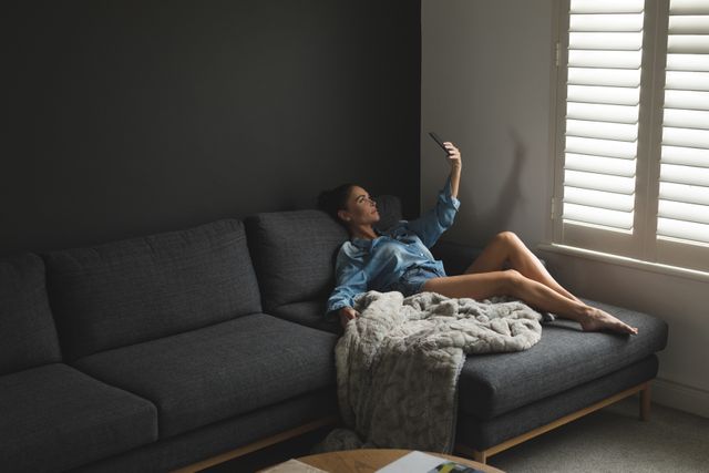 Woman Taking Selfie While Relaxing on Sofa in Cozy Home - Download Free Stock Photos Pikwizard.com