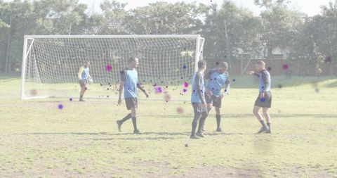 Amateur soccer players practicing defensive drill near goal on sunny grass pitch