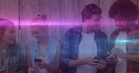 Group of Young Friends Engaging with Smartphones Under Vibrant Lights