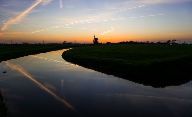 Scenic sunset view with windmill and canal in Dutch countryside - Download Free Stock Photos Pikwizard.com