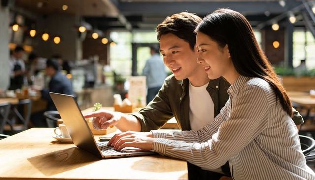 Young couple collaborating on laptop in sunlit cafe for remote work and planning