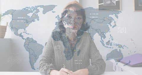 Asian woman writing at home office desk with global data overlay, remote work concept