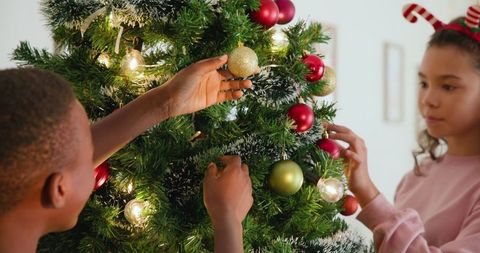 Children Joyfully Decorating Christmas Tree with Ornaments