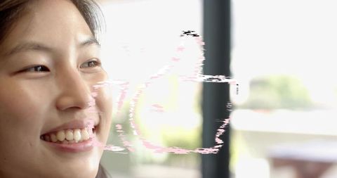 Smiling korean woman gazing through window with pink glitch overlay, soft backlit portrait