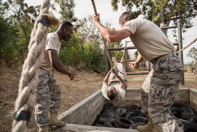 Military soldiers actively training on an obstacle course, emphasizing teamwork and physical fitness. Ideal for illustrating concepts related to military training, perseverance, and collaborative efforts. Perfect for use in articles, advertisements, and materials promoting military services and fitness training programs.