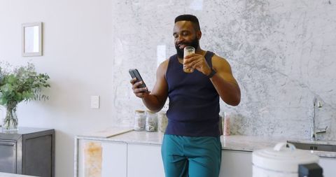 Man Relaxing with Smartphone and Drink in Contemporary Kitchen