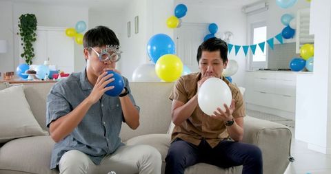 Father and son preparing for party with indoors balloon decoration