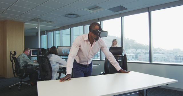 African american businessman using vr headset, with colleagues using computers at office - Download Free Stock Photos Pikwizard.com