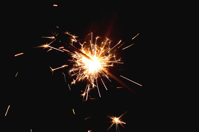 Close up view of burning sparkler against dark background. festivity and celebration concept