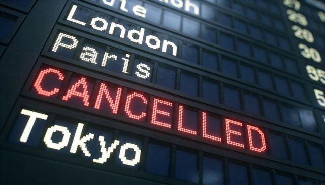 Airport departure board showing cancelled in red with london paris tokyo destinations