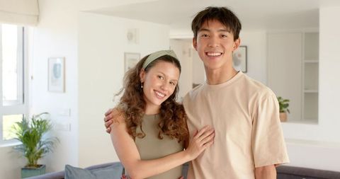 Smiling young couple embracing in bright modern living room with neutral tones