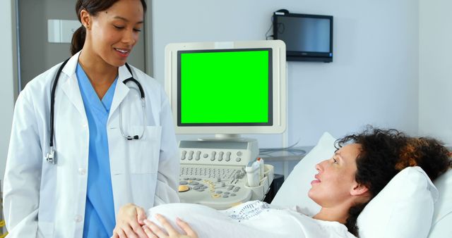 Pregnant woman lying on examination table, receiving prenatal checkup from female doctor at medical clinic. Perfect for topics on maternity care, prenatal health, medical professions, women's health and wellness.