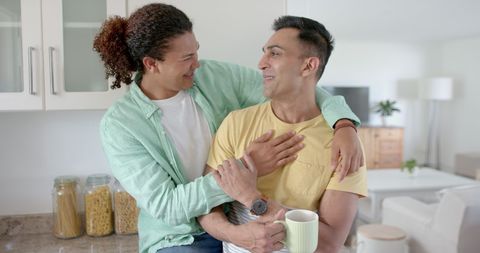 Happy Gay Couple Embracing with Coffee in Kitchen