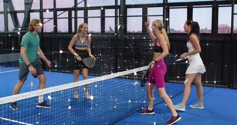 Indoor padel doubles celebrating victory on blue court, mixed players enjoying game