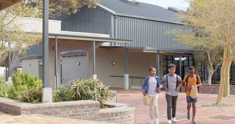 Diverse friends walking on school campus with backpacks