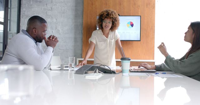 Businesswoman presenting data to colleagues in modern office. Perfect for illustrating teamwork, corporate meetings, business presentations, and entrepreneurial discussions in blogs, websites, and marketing materials.