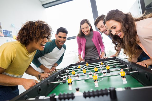 Happy executives playing table football in office
