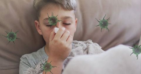 Caucasian boy sneezing with virus elements in pandemic context