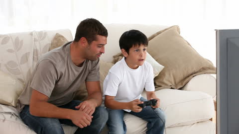 Father and Son Bonding While Playing Video Games on Sofa