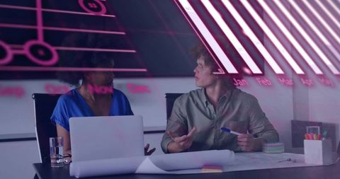 Neon-lit teamwork meeting with diverse coworkers reviewing plans in modern office