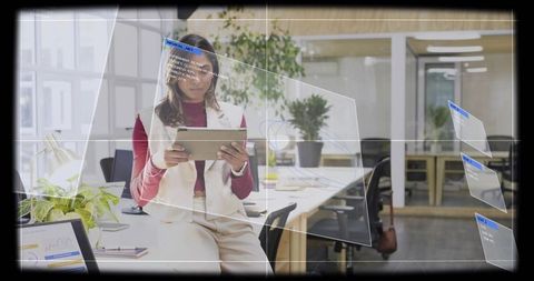 Indian professional holding tablet in modern office with futuristic transparent ui overlays