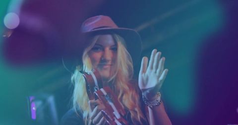 Female Musician Vibrantly Performing On Stage Waving at Crowd