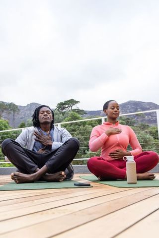 African american couple practicing mindful breathing on deck yoga mats outdoor wellness retreat