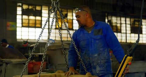 Worker Operating Chain Hoist in Industrial Factory Setting