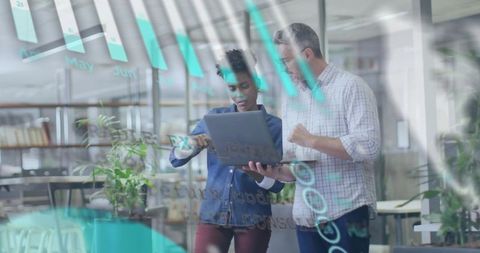 Colleagues collaborating on laptop with teal data overlays and charts in modern office