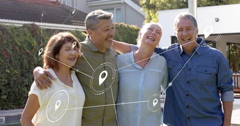 Smiling mature friends linking arms in suburban backyard with digital location-pin overlay
