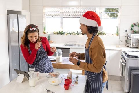 Hispanic woman and african american man baking festive holiday treats in modern kitchen