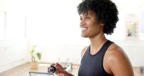 Smiling Yoga Instructor Holding Essential Oils in Bright Studio