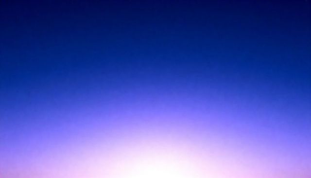 Glowing horizon gradient twilight bathing sky in deep blue, violet and soft pink