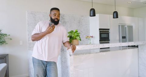 Man Using Smartphone While Relaxing in Modern Kitchen
