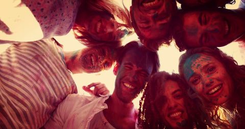 young adults gathered, smiles wide, covered in vivid powders representing unity and celebration. perfect for illustrating themes of togetherness, happiness, and cultural festivals such as holi or color run events. suitable for use in advertisements, blog posts, or social media campaigns that celebrate community and diversity.