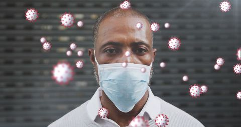African american man wearing face mask with covid-19 cells overlay